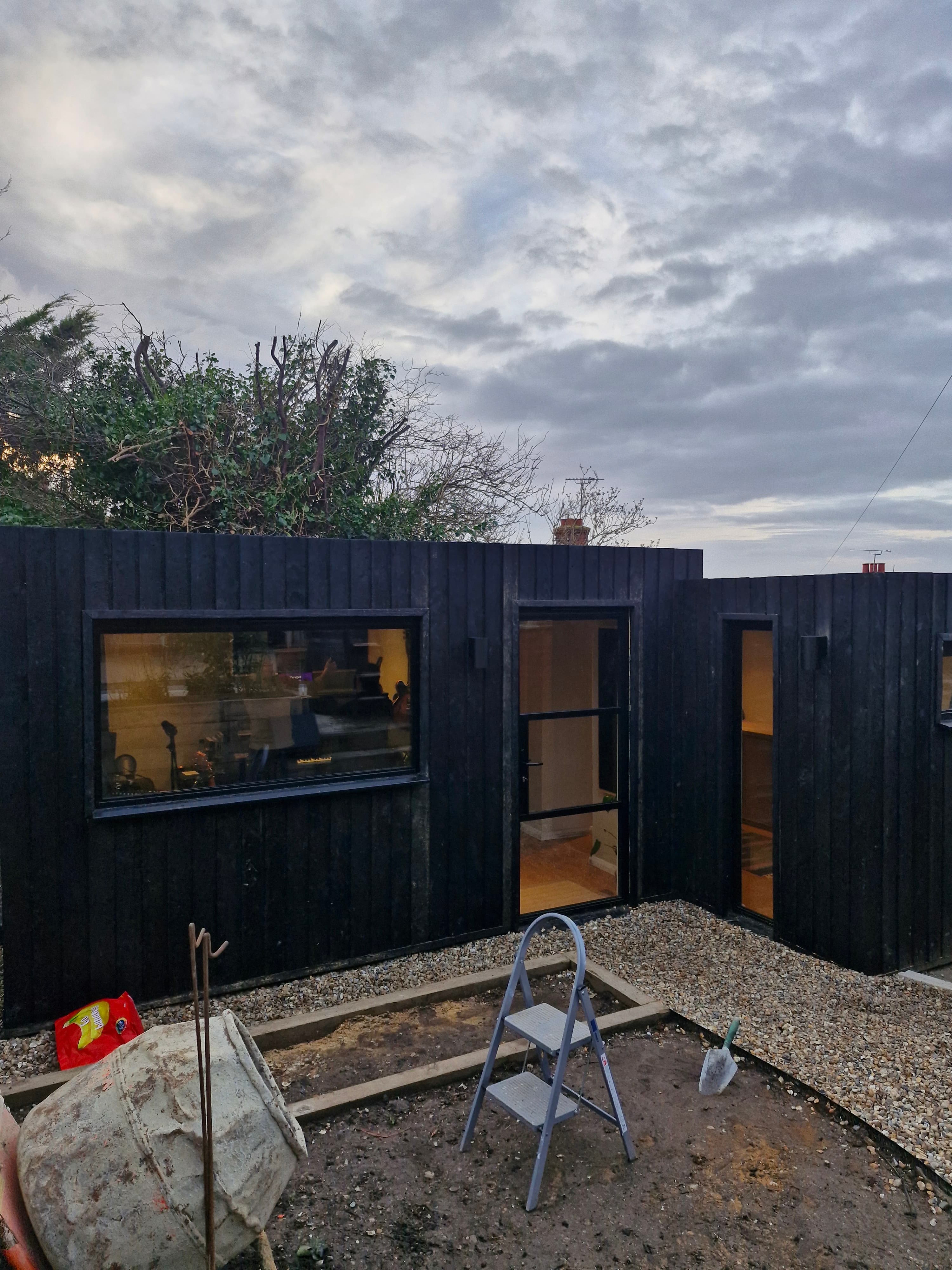 Dark timber garden studio exterior with landscaped surroundings