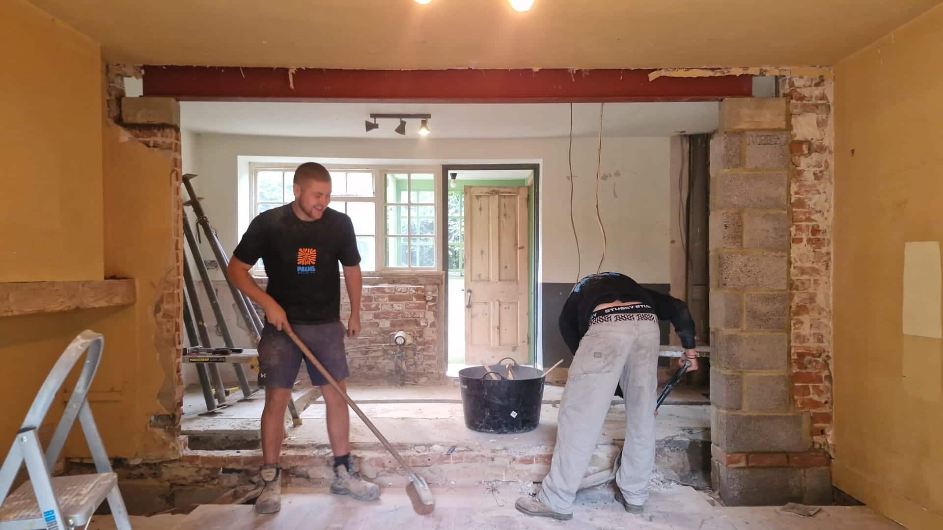 Two Palms Build.Co team members clearing out a room after removing a wall for an extension