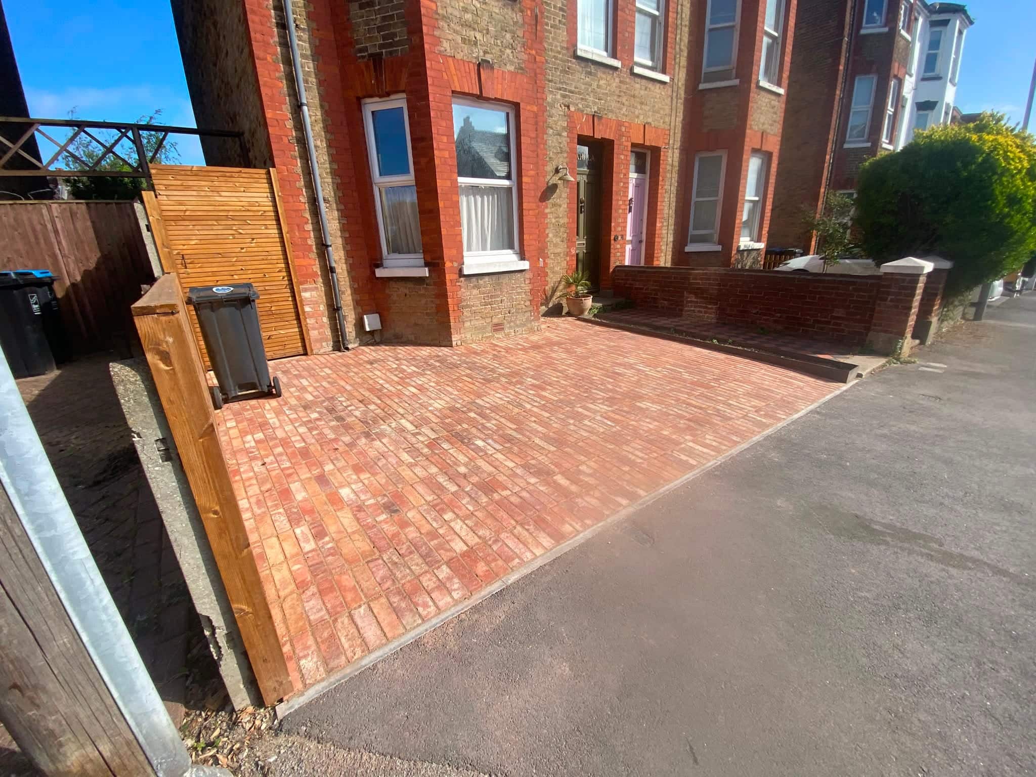 Finished clay-paver driveway in front of a red-brick Victorian terrace, with a new slatted timber bin screen