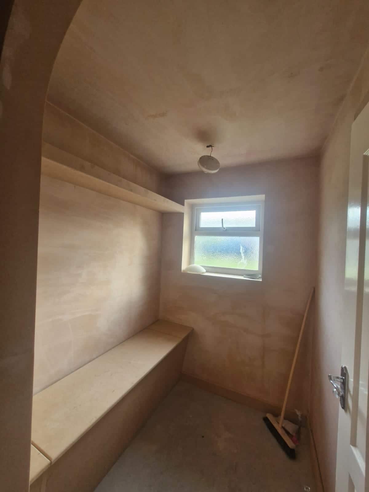 Arched MDF alcove and built-in bench seat with a floating shelf, freshly plastered and awaiting paint