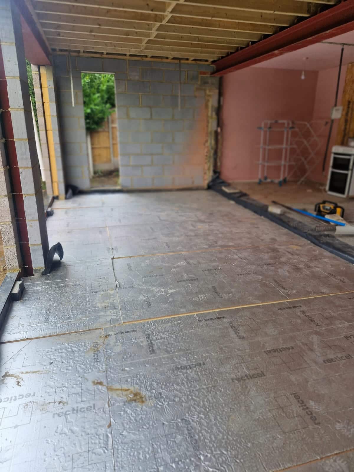 Insulation boards laid over a new extension floor, with blockwork walls and a steel beam overhead